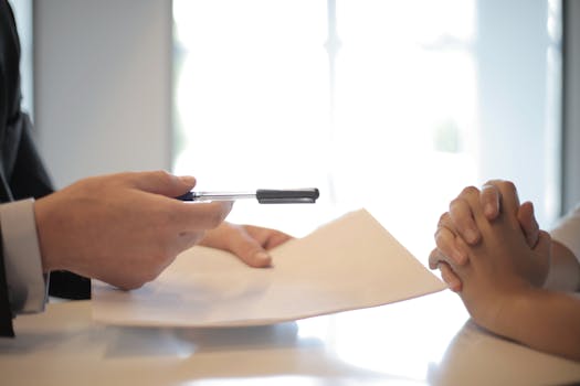 Home Close-up of a contract signing with hands over documents. Professional business interaction.